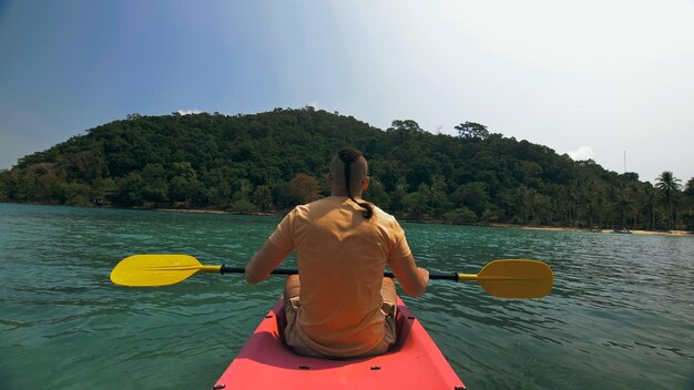 Foto homem com óculos de sol e chapéu enfileira canoa de plástico rosa ao longo do mar ag