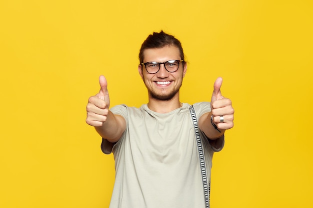 Homem com óculos sorrindo e mostrando o polegar para cima, gesto com as duas mãos