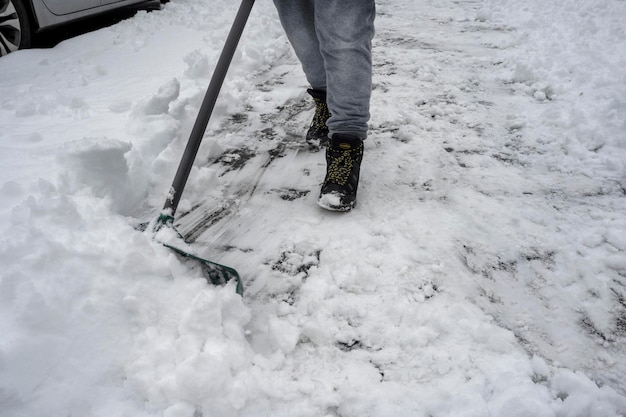 Homem com pá de neve limpa calçadas no inverno durante nevascas Tempestade de neve e nevascas fortes