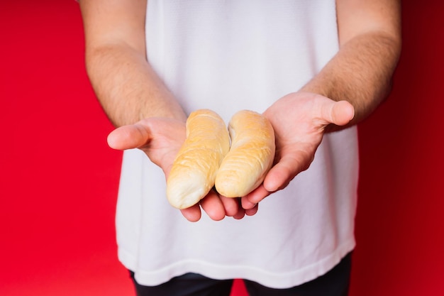 Homem com pão fresco nas mãos isolado no estúdio de fundo vermelho