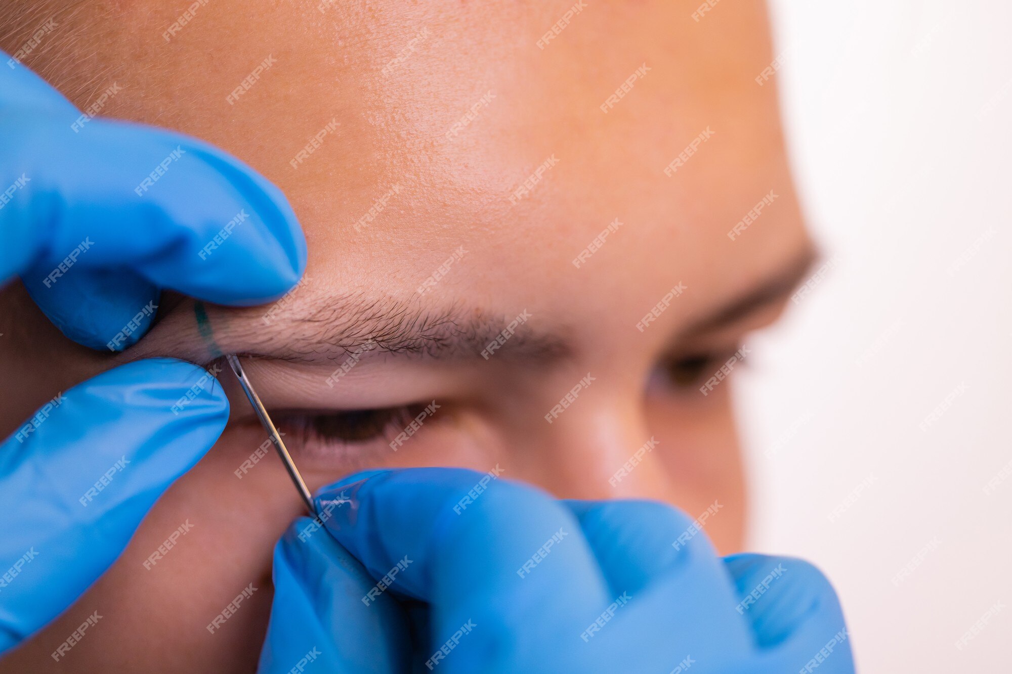 Homem com piercing na sobrancelha. três pequenos piercings pretos.