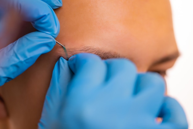 Homem com piercing na sobrancelha. três pequenos piercings pretos