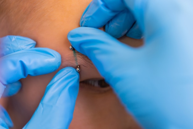 Homem com piercing na sobrancelha. três pequenos piercings pretos