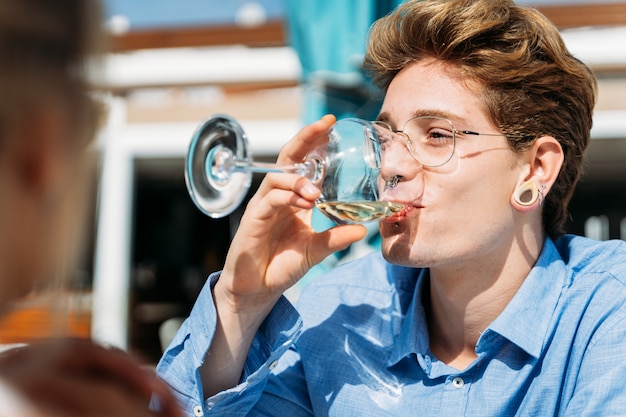 Homem com piercings bebendo vinho branco no terraço