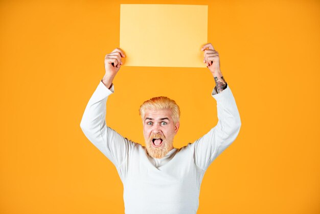 Homem com placa de publicidade em branco de papel na cor de fundo Modelo masculino segurando placa branca Copiar espaço