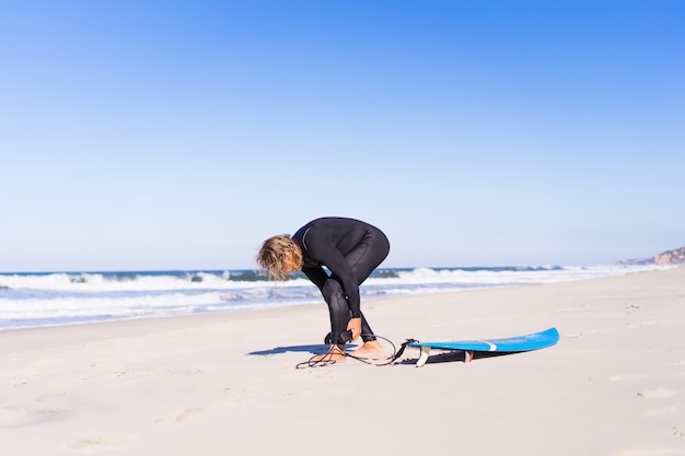 Foto homem com prancha de surf na costa do oceano. surfista em terno molhado