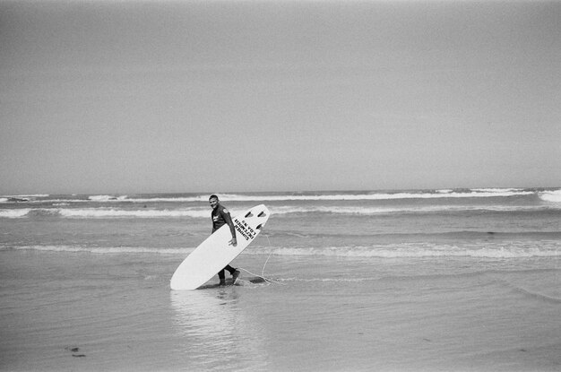 Foto homem com prancha de surf na praia contra o céu claro