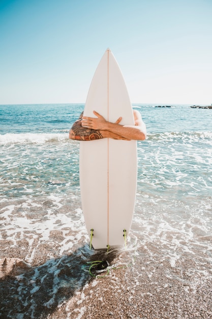 Homem com prancha de surf na praia perto do mar