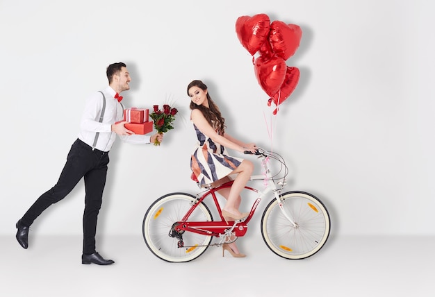 Homem com presentes de dia dos namorados e garota na bicicleta