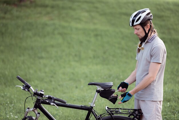 Homem com quebra de bicicleta conserta sua bicicleta na rua