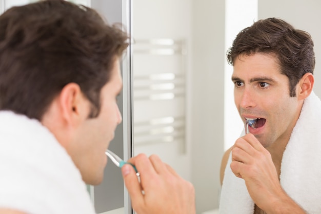 Homem, com, reflexão, dentes escovando, em, a, banheiro