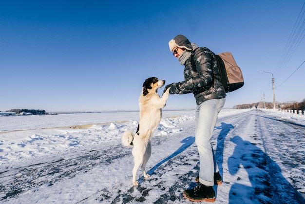 Homem com roupas de inverno, cuidando do cachorro sem teto.