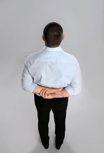 Homem com roupas formais na vista traseira de fundo cinza