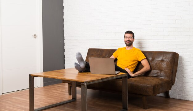 Homem, com, seu, laptop, em, um, sala, posar, com, braços quadril, e, sorrindo