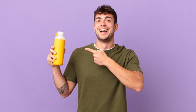 homem com smoothy parecendo animado e surpreso apontando para o lado e para cima para copiar o espaço