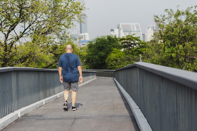 Homem com sobrepeso a fazer exercício a caminhar para queimar gordura no parque da cidade