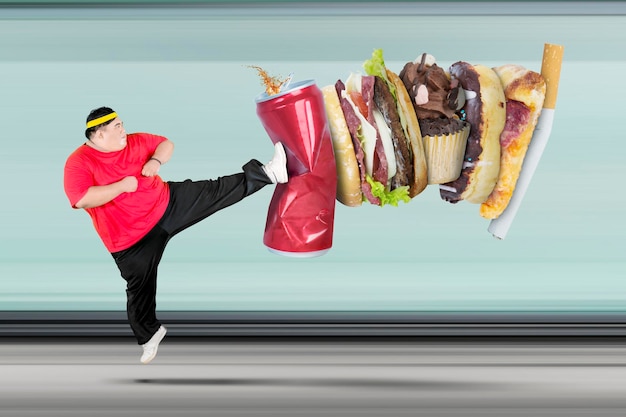 Homem com sobrepeso chutando refrigerante e fast food