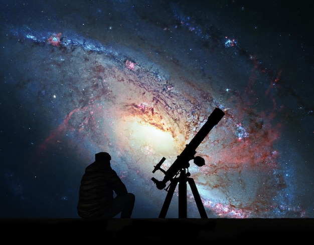 Foto homem com telescópio olhando para as estrelas. spiral galaxy m106, na constelação de canes venatici. os elementos desta imagem são fornecidos pela nasa.
