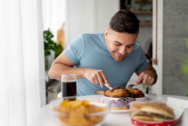 Foto homem com transtorno alimentar tentando comer frango