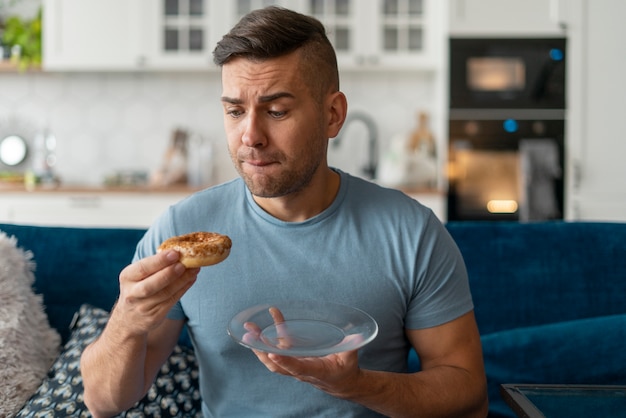 Foto homem com transtorno alimentar tentando comer rosquinha