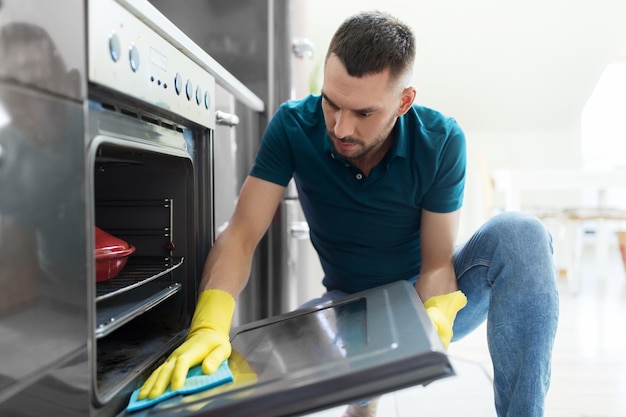 homem com trapo limpando a porta do forno na cozinha da casa