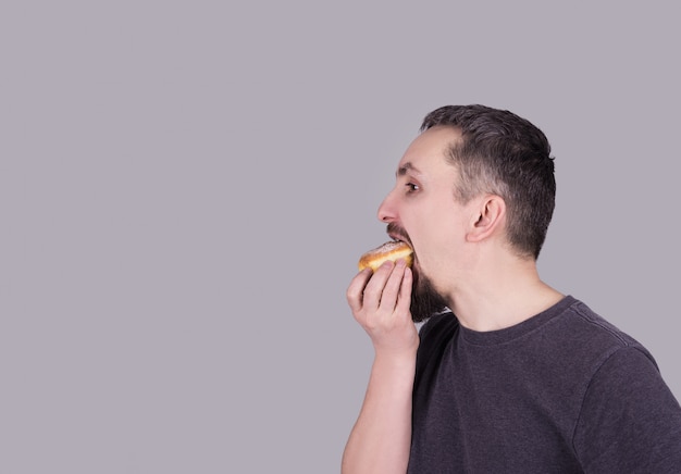 Foto homem, com, um, barba, comer, um, coque, sobre, experiência cinza