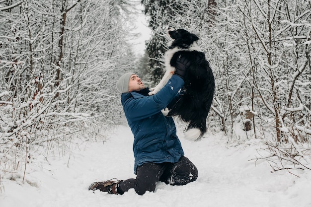 Homem com um cachorro border collie preto e branco na neve