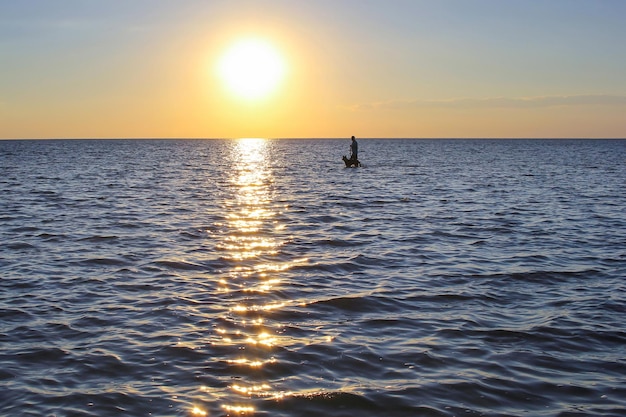 Homem com um cachorro no mar ao pôr do sol um sol