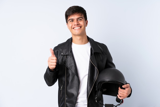 Homem com um capacete de moto sobre azul isolado, dando um polegar para cima gesto