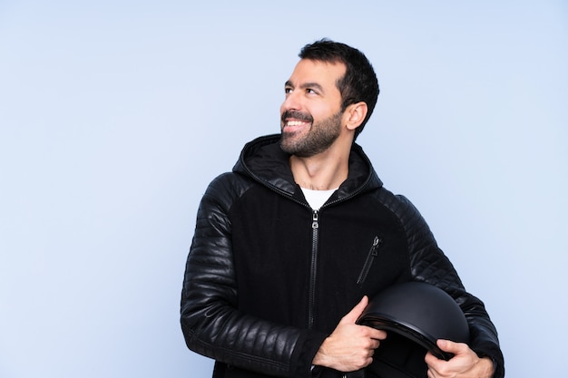 Homem com um capacete de moto sobre parede isolada feliz e sorridente