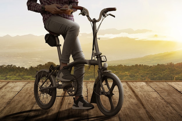 Homem com um celular na bicicleta no caminho de madeira