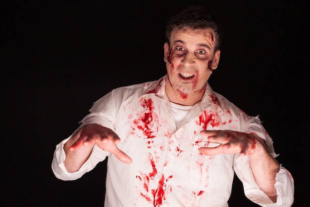 Homem com um demônio dentro de seu corpo e sangue isolado em um fundo preto. Maquiagem criativa de Halloween.