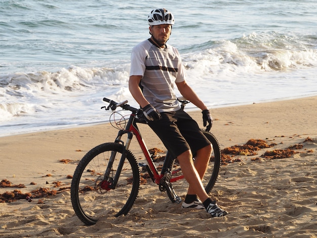 Homem com uma bicicleta descansando na praia