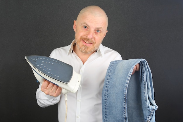 Homem com uma camisa branca com uma chapinha de ferro e jeans nas mãos