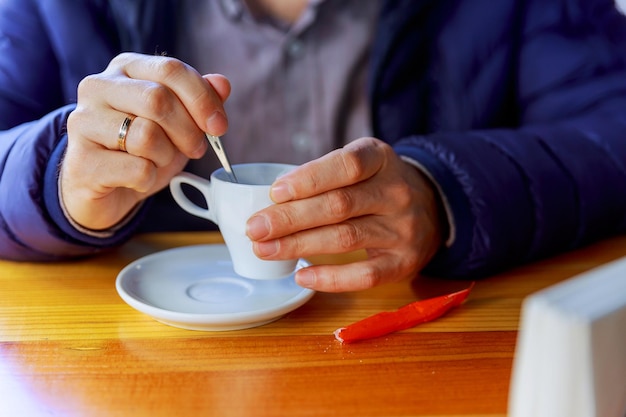 Homem com uma xícara de café jovem do sexo masculino em roupas casuais tomando bebida quente no café e olhando para w