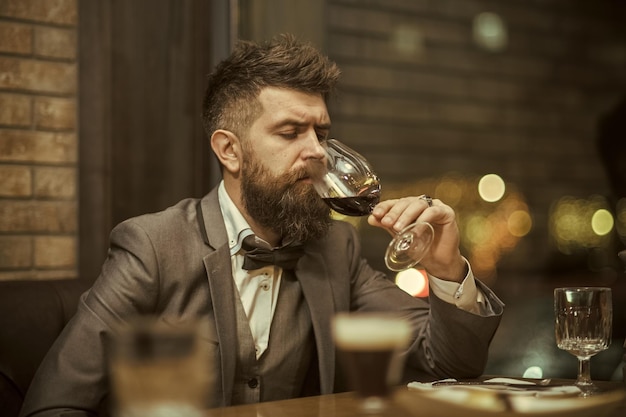 Homem com vinho Homem de vinho tinto avalia a cor do vinho em um copo Sommelier provando vinho tinto