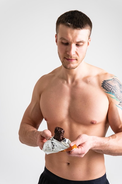 Homem come barra de proteína em fundo branco isolado sabor de comida de proteína atleta pessoa mulher treino