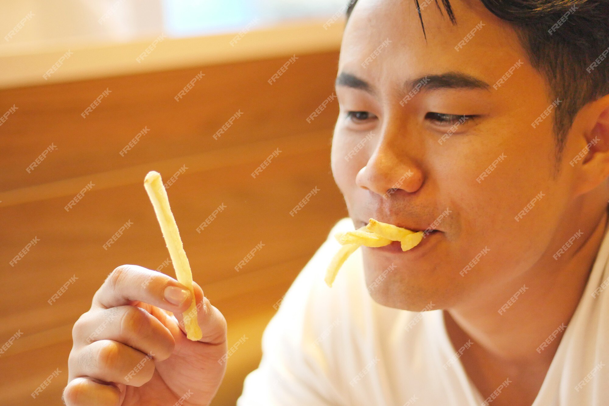 Jovem macho comendo batata frita enquanto espera o filme terminar na  superfície branca