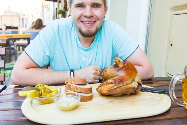 Homem comendo junta de porco e bebendo cerveja