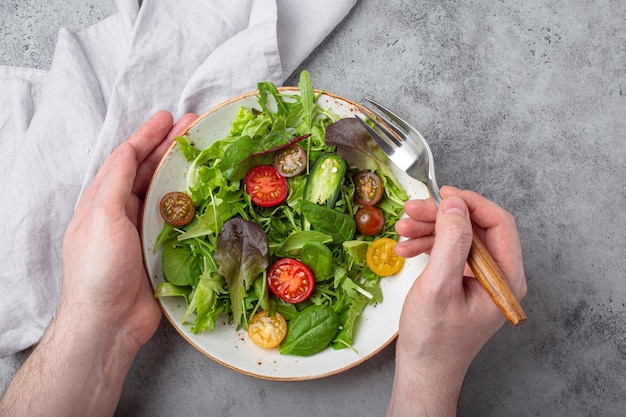 Homem comendo salada saudável de vegetais vegetarianos com tomate cereja vermelho e amarelo