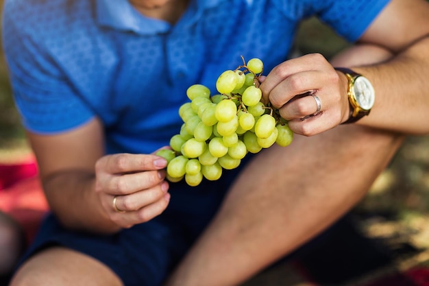 Homem comendo uvas em um piquenique de verão no parque