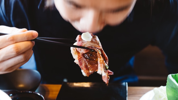 Homem comer toucou a cobertura rara rara média do sushi da carne de wagyu do japonês com alho fresco.