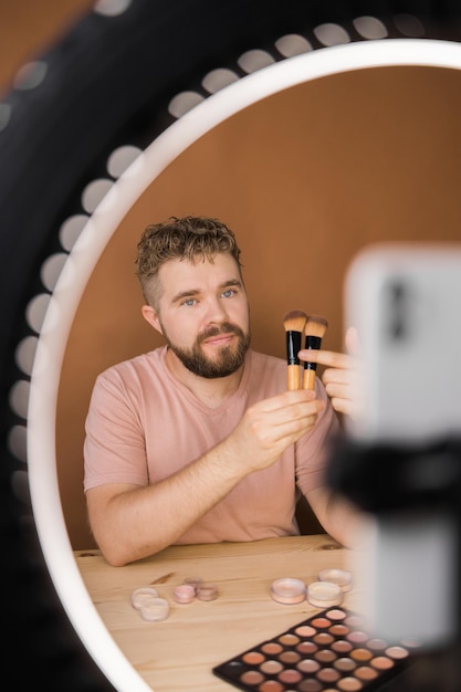 Homem compõe vlogger gravando transmissão sobre cosméticos e tutoriais para maquiadores