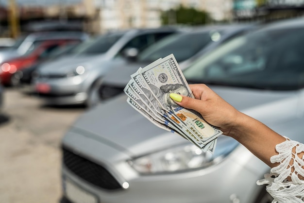 Homem compra um carro moderno segurando dólar contra automóvel no conceito de venda de volta