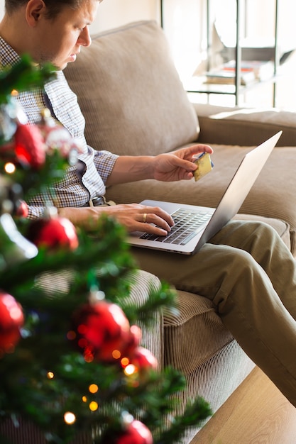 Homem comprando presentes de Natal de ano novo on-line usando o laptop do telefone