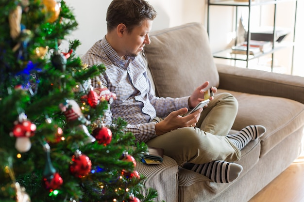 Homem comprando presentes de Natal de ano novo on-line usando o laptop do telefone