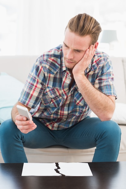 Homem concentrado usando o telefone móvel perto do papel rasgado