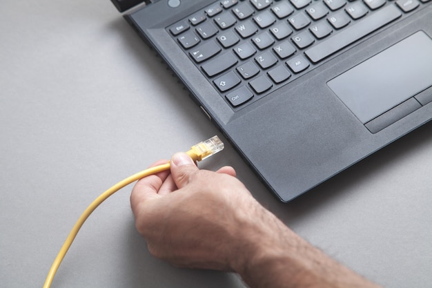 Homem conecta o cabo de rede ao laptop.