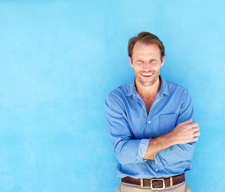 Foto homem confiante bonito sorrindo contra parede azul