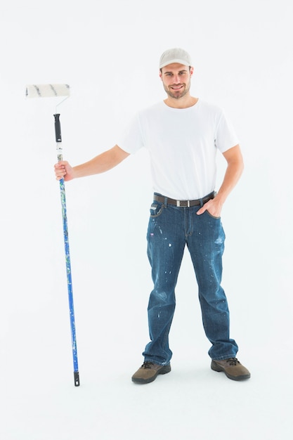 Foto homem confiante segurando rolo de pintura no fundo branco